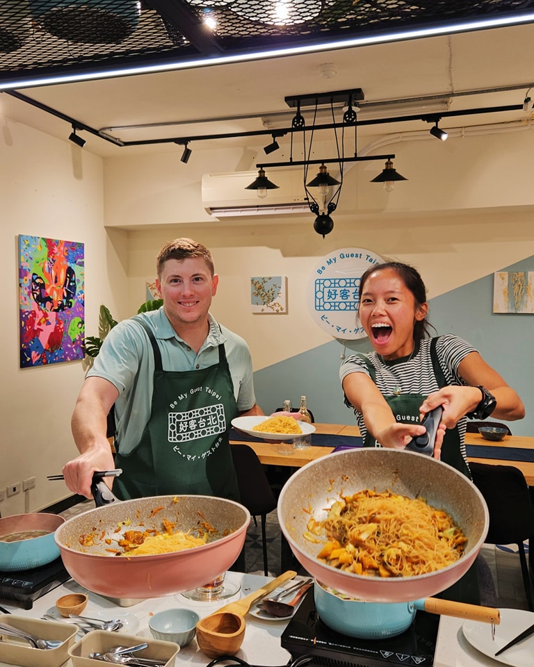 a man and woman smiling and holding a bowl of food at BeMyGuest Taipei